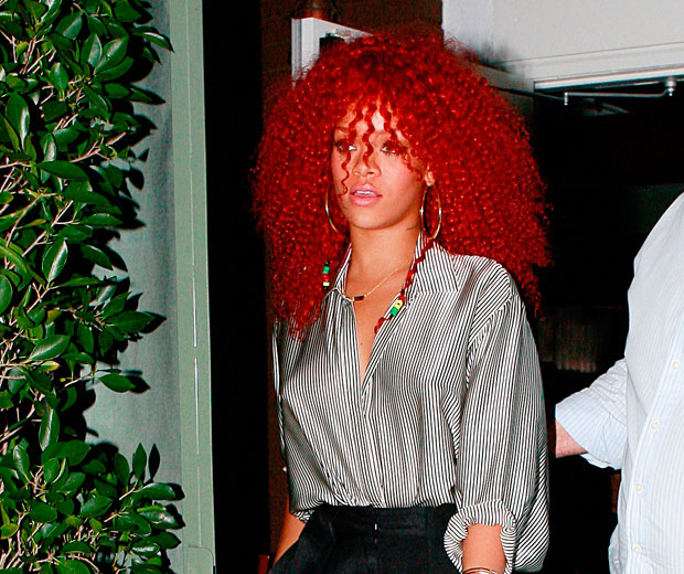 Rihanna steps out with a big, bouncy, crimped afro hairstyle in her trademark red hue.