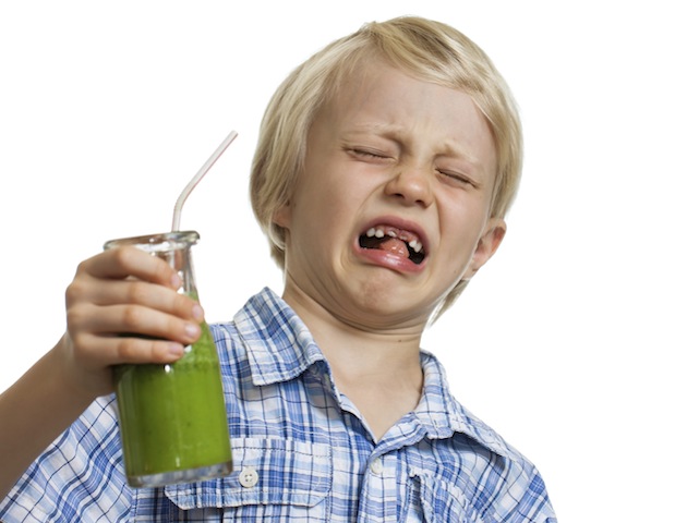 Awkward questions kids ask: Boy pulling funny face holding green smoothie