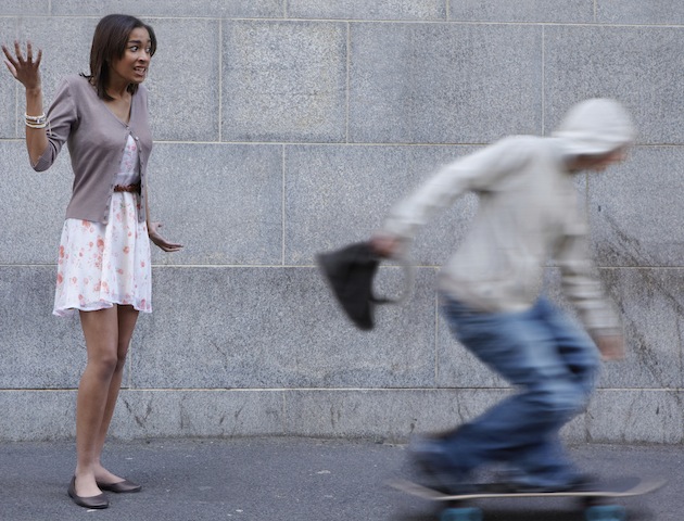 Woman having bag snatched by man on a skateboard