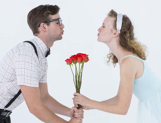 image of girl and boy air kissing over a bunch of flowers