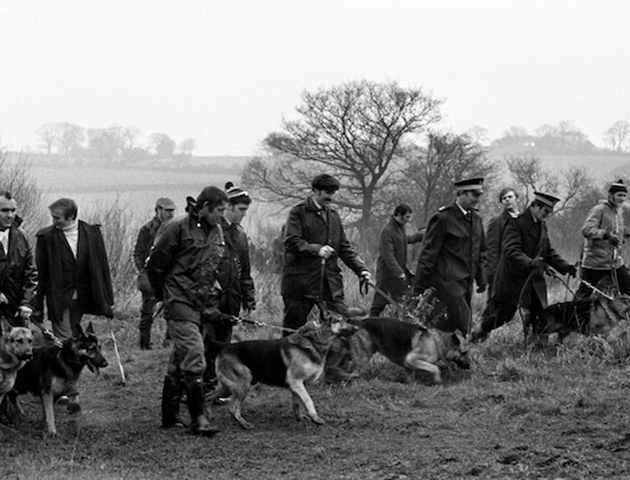 Police with tracker dogs search waste ground to look for clues connected with the kidnap. (Photo: PA Photos)