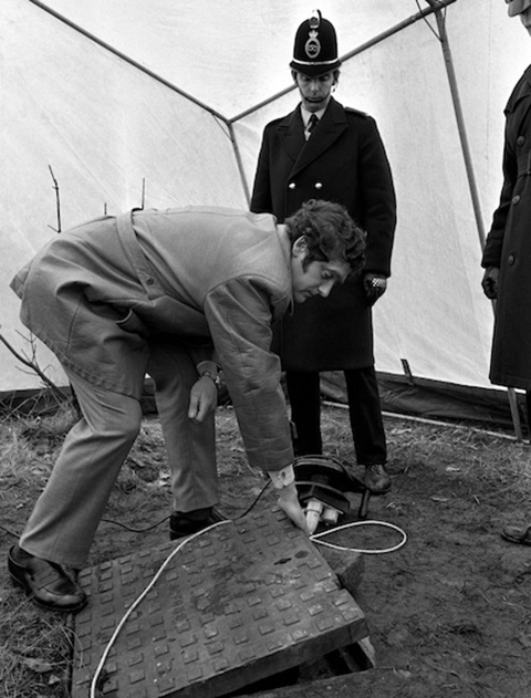Police raise a manhole cover at Bathpool Park, Kidsgrove, to examine the entrance to the shaft. (Photo: PA Photos)