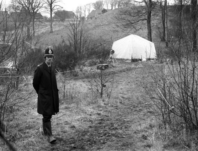 Policeman stands by spot where manhole cover over drain where Lesley Whittle's body was found