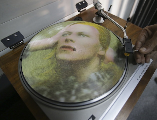 Rene Rivo, a Filipino David Bowie fan, plays a picture disc of David Bowie's Hunky Dory on a turntable at his shop in suburban Paranaque, south of Manila, Philippines on Tuesday, Jan. 12, 2016. Bowie, the chameleon-like star who transformed the sound - and the look - of rock with his audacious creativity and his sexually ambiguous makeup and costumes, died of cancer Sunday, Jan. 10. (AP Photo/Aaron Favila)