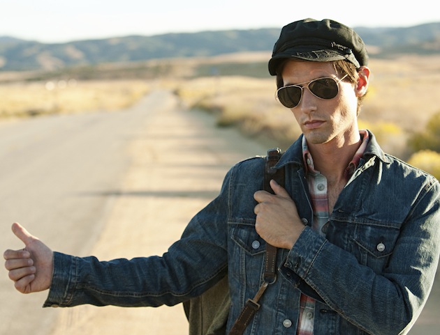 Young man hitchhiking at roadside