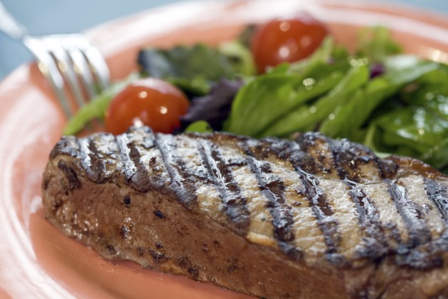 A plate with a big juicy steak and salad.