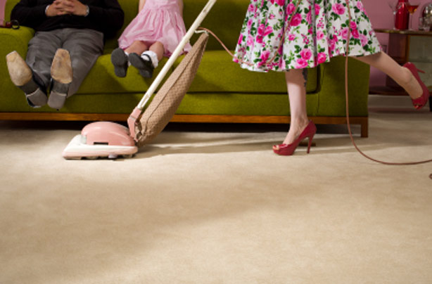 Woman hoovering under husband's feet