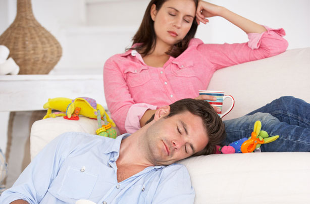 Parents sleeping surrounded by toys