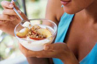 A woman eating yogurt and fruit