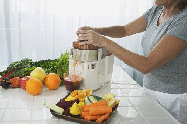 A woman in the kitchen preparing vegetable and fruit juice smoothie