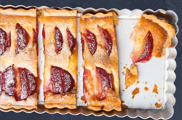 Un gros plan d'une tarte aux prunes coupée à la main.up d'une tarte aux prunes coupée en tronçons. Les prunes sont des fruits de saison en septembre.