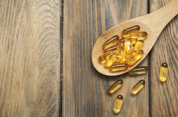 Vitamin D foods cod liver oil displayed on a wooden spoon.