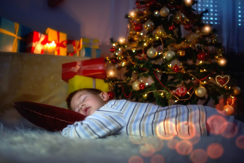 christmas traditions, kid sleeping under christmas tree