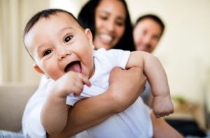 laughing baby being held by parents