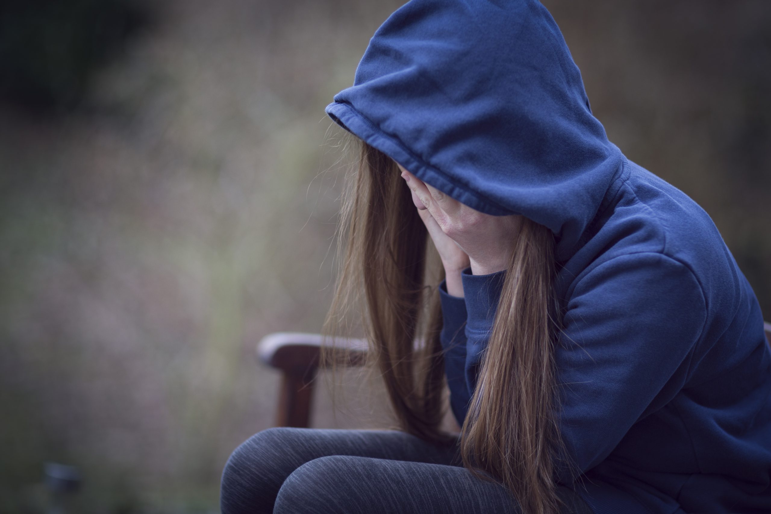 Teenage girl with head in hands exhibiting signs of bullying.