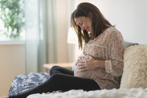 woman looking down at pregnant stomach - boy or girl quiz