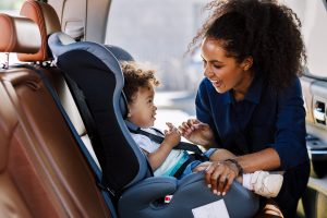 woman strapping toddler into car set - car seat safety tips