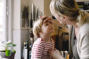 Mum checking young boy for coronavirus symptoms in kids