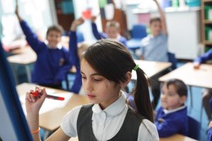 girl drawing on whiteboard at school - will pubs close when schools reopen