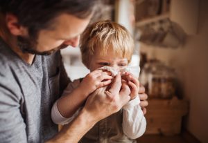 child blowing his nose - can kids go to school with a cold