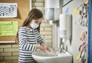 girl with face mask washing hands