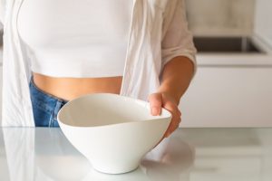 A woman skipping a meal with an empty bowl