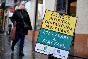 Covid-19 physical distancing sign with lockdown working in Scotland