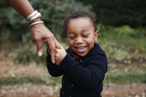 child holding hand in a park - children are thought to be the last to receive the Pfizer vaccine